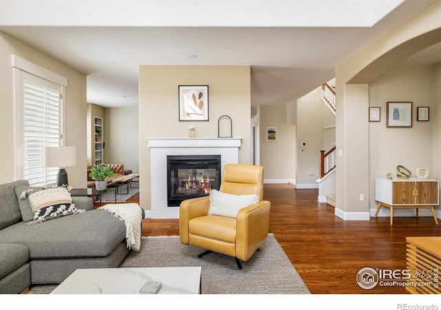 301 Indian Peaks Trl W, Lafayette, CO 80026 - living area with arched walkways, a glass covered fireplace, baseboards, wood finished floors, and stairway