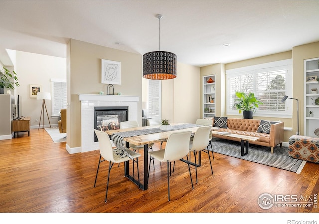 301 Indian Peaks Trl W, Lafayette, CO 80026 - dining room featuring baseboards, a glass covered fireplace, built in features, and wood finished floors