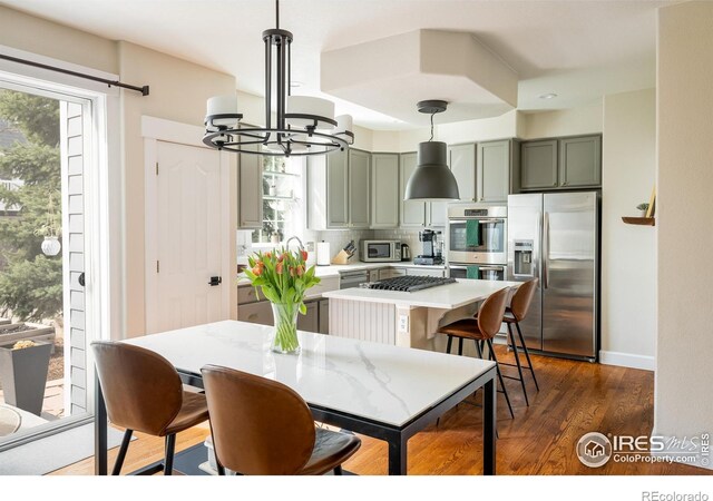 301 Indian Peaks Trl W, Lafayette, CO 80026 - kitchen with an inviting chandelier, light countertops, stainless steel appliances, decorative backsplash, and a wealth of natural light