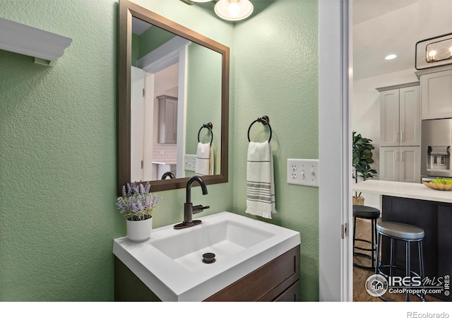 bathroom featuring a textured wall, vanity, and recessed lighting