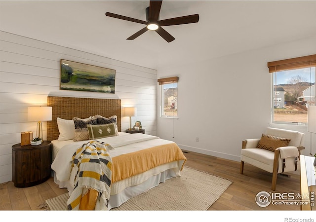 bedroom with wood finished floors, wood walls, and multiple windows