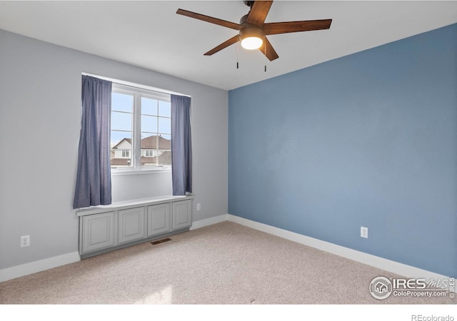 carpeted spare room with ceiling fan, baseboards, and visible vents