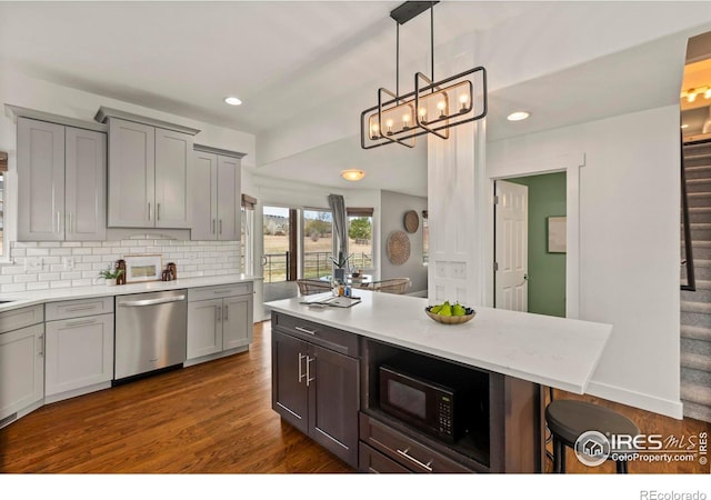 kitchen with dishwasher, light countertops, a kitchen breakfast bar, black microwave, and backsplash
