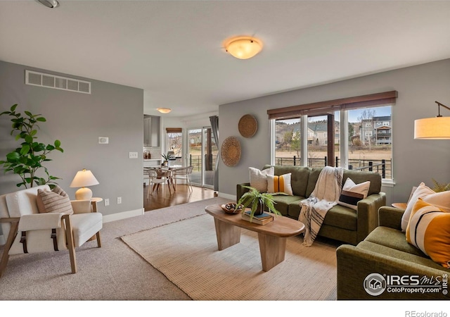living room with visible vents, baseboards, and light carpet