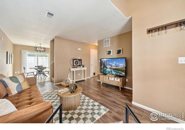 living area with a notable chandelier, visible vents, and wood finished floors