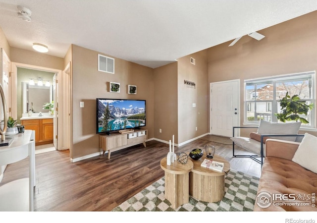 living room featuring wood finished floors, baseboards, and visible vents