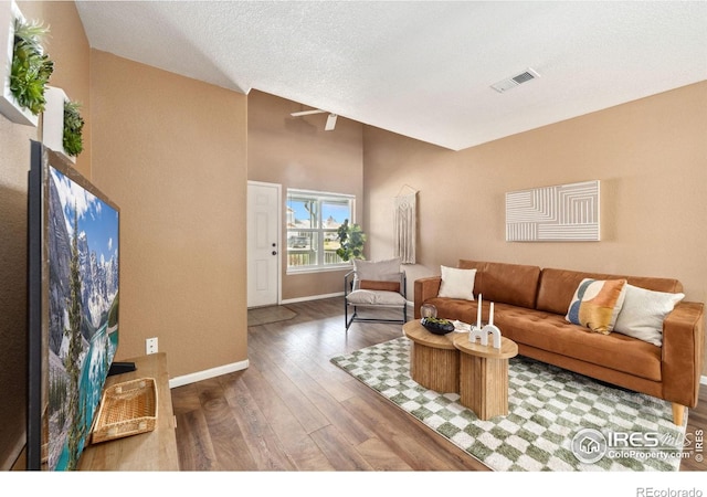 living area featuring visible vents, baseboards, wood finished floors, and a textured ceiling