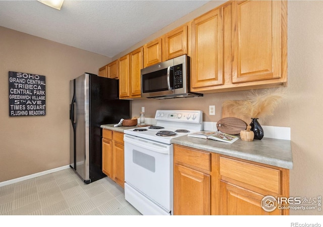 kitchen with light countertops, appliances with stainless steel finishes, baseboards, and a textured ceiling