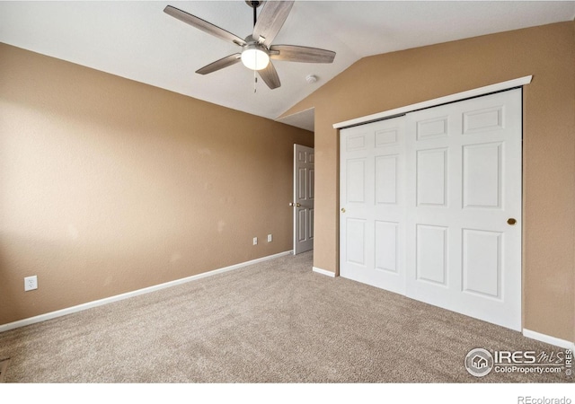 unfurnished bedroom featuring ceiling fan, carpet, a closet, lofted ceiling, and baseboards