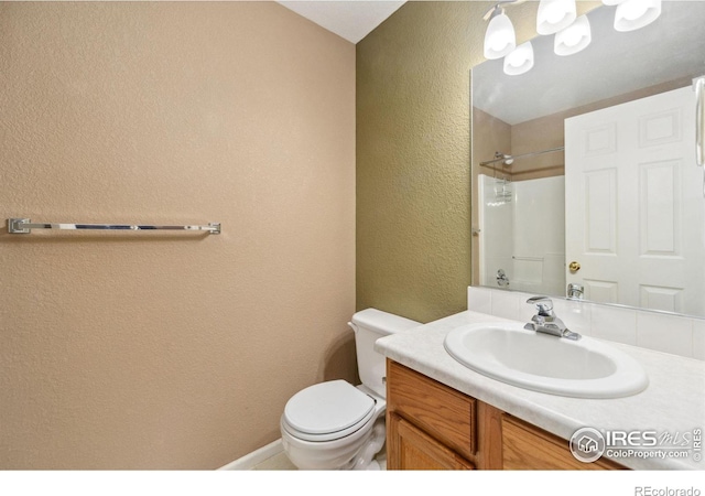 full bath with toilet, vanity, a textured wall, and walk in shower