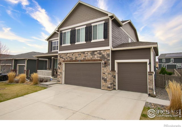 craftsman-style house featuring stone siding, a garage, fence, and concrete driveway