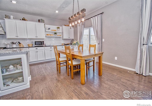 dining area with a textured ceiling, baseboards, and wood finished floors