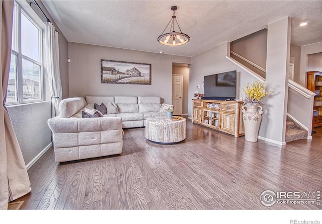 living room with a textured ceiling, baseboards, stairs, and wood finished floors
