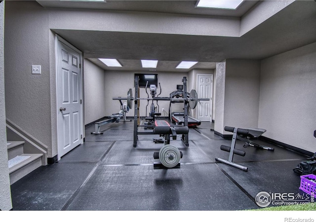 workout room featuring baseboards and a textured wall