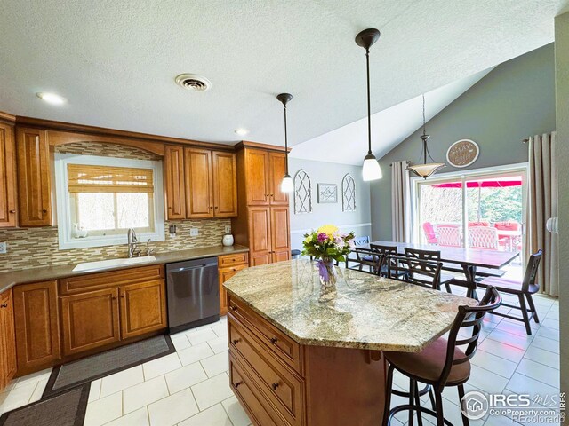 kitchen with visible vents, dishwasher, a center island, a sink, and brown cabinetry