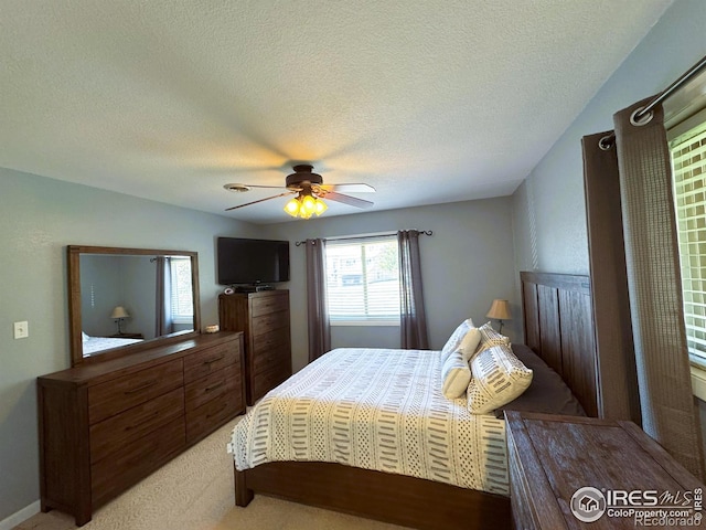 bedroom with a textured ceiling, a ceiling fan, and light colored carpet
