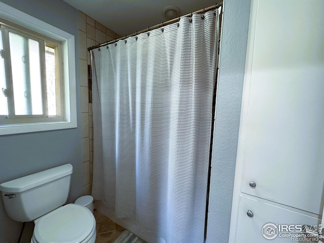 bathroom featuring toilet, shower / bath combination with curtain, and tile patterned flooring