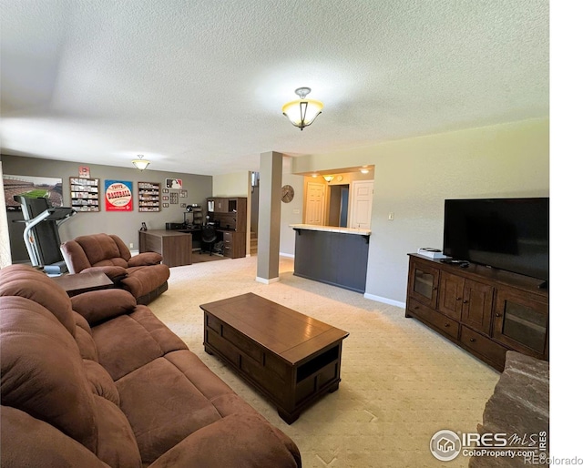 living area featuring light colored carpet, baseboards, and a textured ceiling