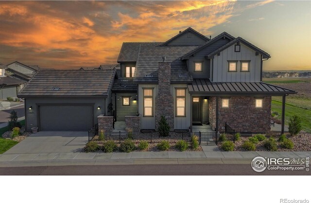 1563 Stoneseed St, Berthoud, CO 80513 - view of front of home with an attached garage, stone siding, board and batten siding, driveway, and a fenced front yard