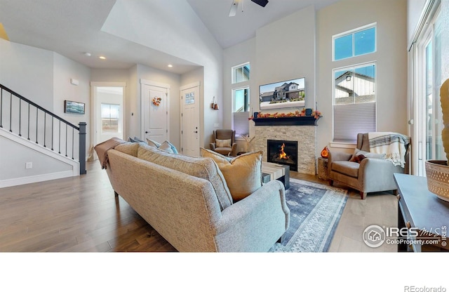 1563 Stoneseed St, Berthoud, CO 80513 - living area featuring high vaulted ceiling, stairs, ceiling fan, wood finished floors, and a stone fireplace