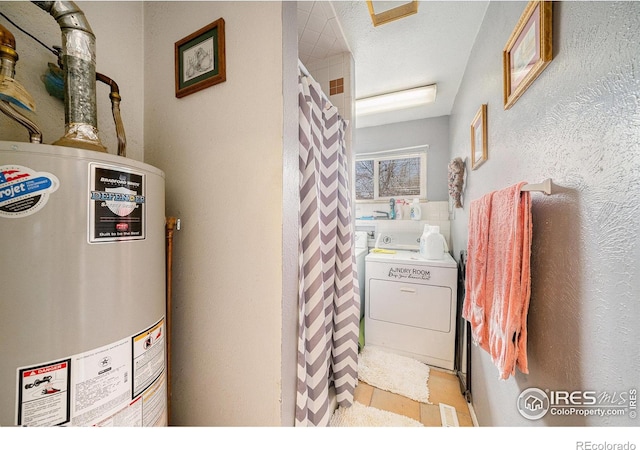 bathroom featuring water heater, a textured wall, washer / dryer, and a textured ceiling