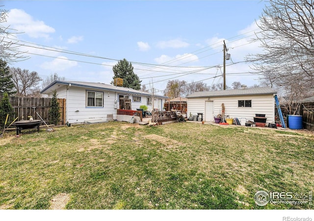 back of house with an outdoor structure, fence, a lawn, a deck, and a chimney
