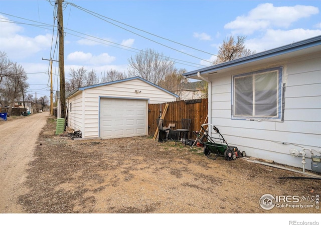 detached garage featuring driveway and fence