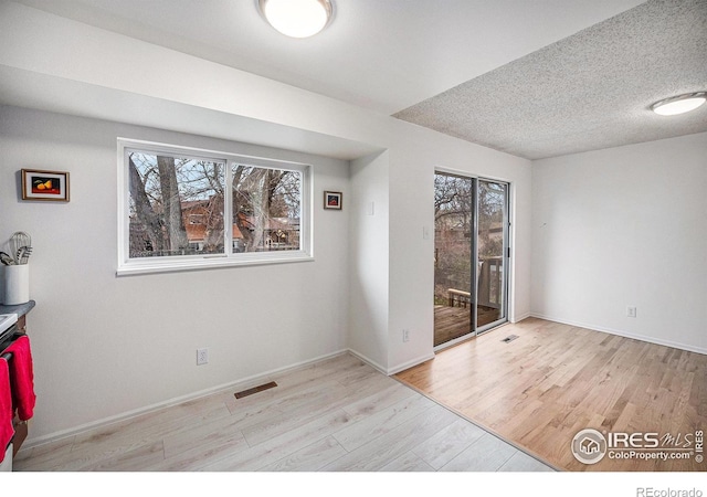 spare room featuring visible vents, wood finished floors, and a healthy amount of sunlight