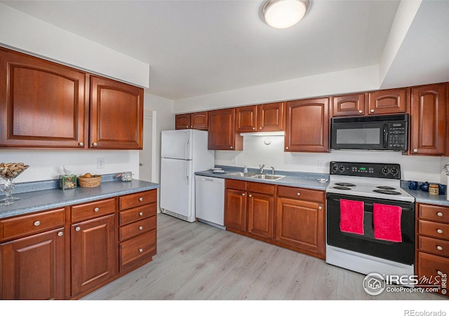 kitchen with white appliances, light wood-style floors, a sink, and brown cabinets