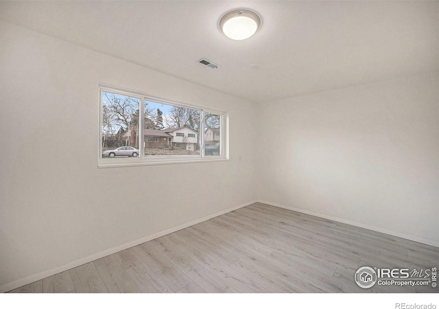 empty room featuring baseboards, visible vents, and wood finished floors
