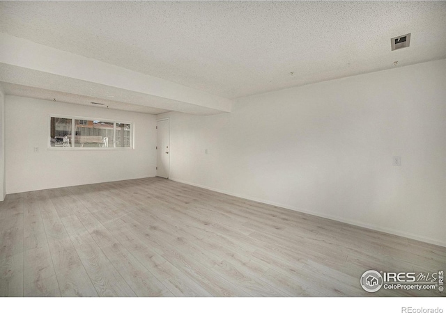 unfurnished room with wood finished floors and a textured ceiling