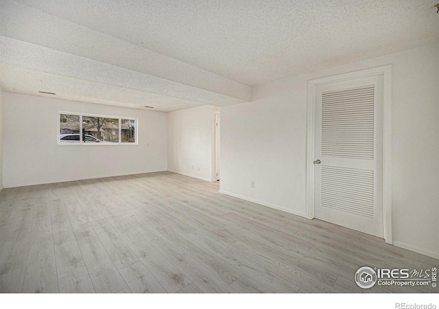 empty room with baseboards, a textured ceiling, and wood finished floors