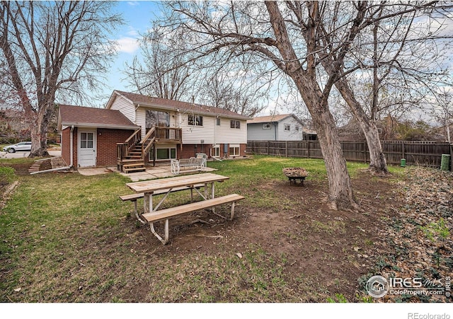 rear view of property with an outdoor fire pit, a yard, brick siding, and fence