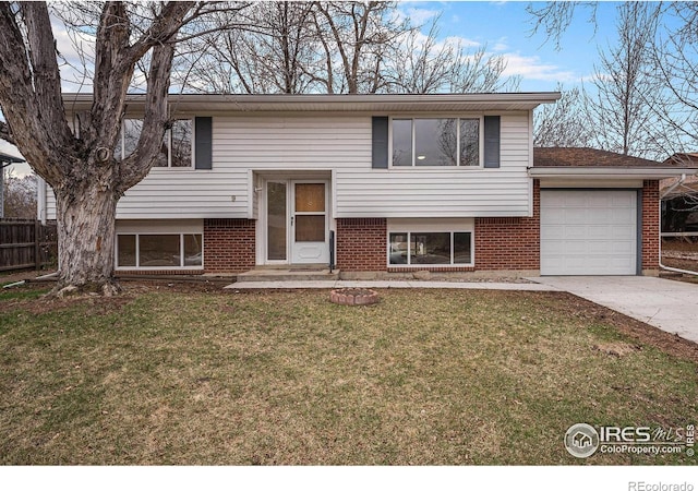 split foyer home featuring brick siding, a garage, concrete driveway, and a front yard