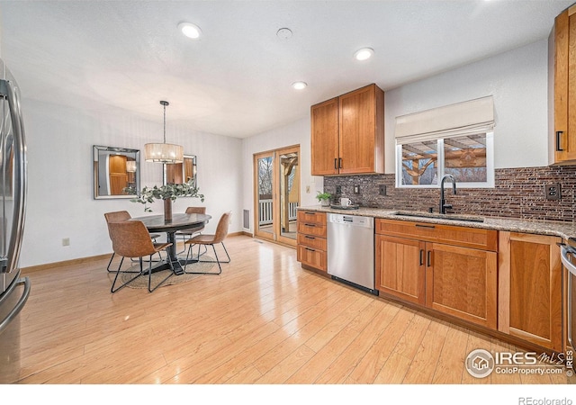 584 Sunwood Dr, Loveland, CO 80538 - kitchen with decorative backsplash, light wood-style flooring, stainless steel dishwasher, a sink, and brown cabinetry