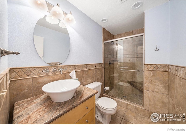 584 Sunwood Dr, Loveland, CO 80538 - bathroom featuring toilet, vanity, a shower stall, wainscoting, and tile walls
