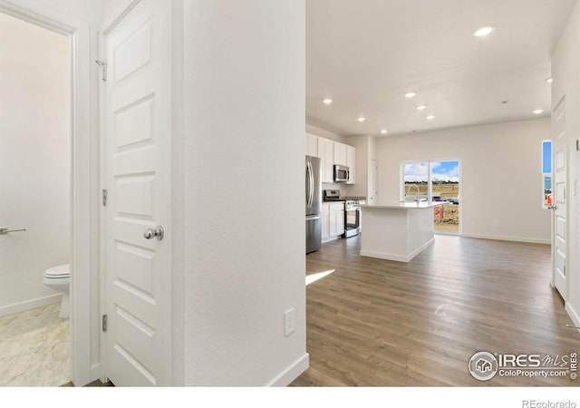 7153 Feather Reed Dr, Wellington, CO 80549 - kitchen with white cabinets, stainless steel appliances, wood finished floors, and recessed lighting