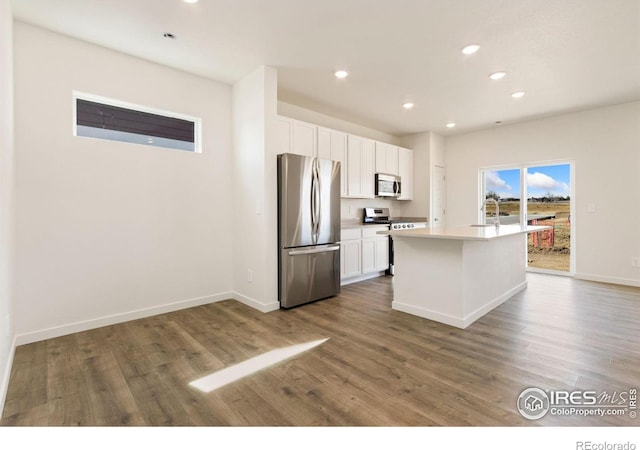 7153 Feather Reed Dr, Wellington, CO 80549 - kitchen featuring baseboards, white cabinets, wood finished floors, and stainless steel appliances