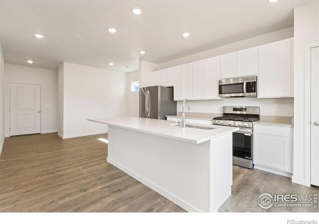7153 Feather Reed Dr, Wellington, CO 80549 - kitchen with light countertops, a sink, an island with sink, light wood finished floors, and appliances with stainless steel finishes