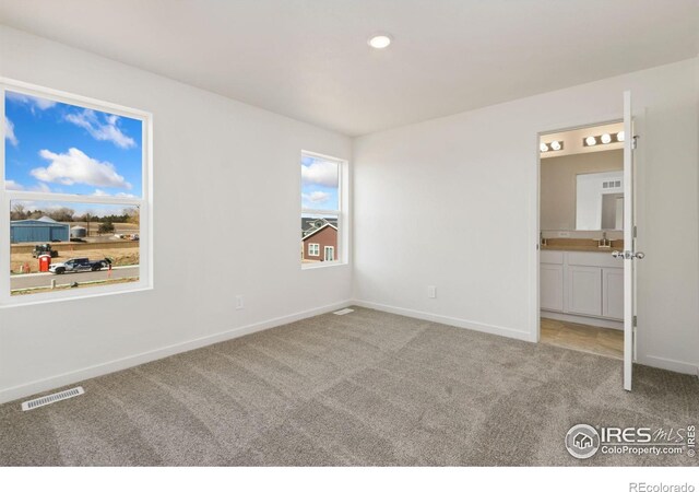 7153 Feather Reed Dr, Wellington, CO 80549 - unfurnished bedroom featuring light colored carpet, baseboards, a sink, ensuite bath, and visible vents