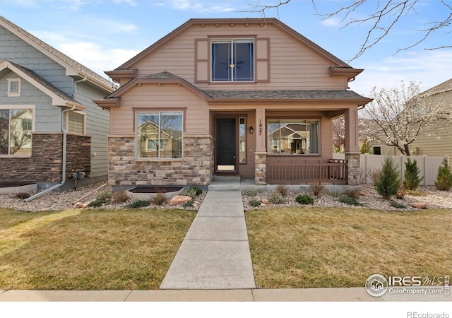 1827 Prairie Ridge Dr, Fort Collins, CO 80526 - view of front facade with stone siding, a porch, fence, and a front lawn