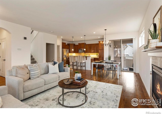 1827 Prairie Ridge Dr, Fort Collins, CO 80526 - living area with dark wood-style flooring, a tile fireplace, stairs, recessed lighting, and arched walkways
