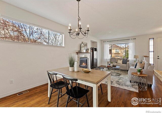 1827 Prairie Ridge Dr, Fort Collins, CO 80526 - dining room featuring visible vents, a lit fireplace, wood finished floors, and a chandelier