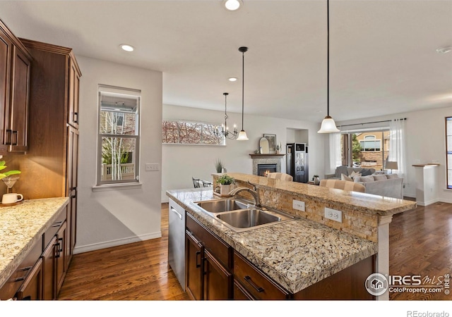 1827 Prairie Ridge Dr, Fort Collins, CO 80526 - kitchen with dark wood-type flooring, a warm lit fireplace, a sink, and stainless steel dishwasher