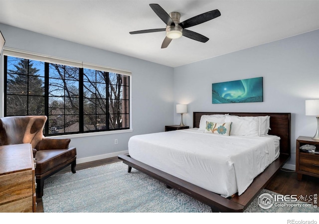 bedroom featuring baseboards, wood finished floors, and a ceiling fan