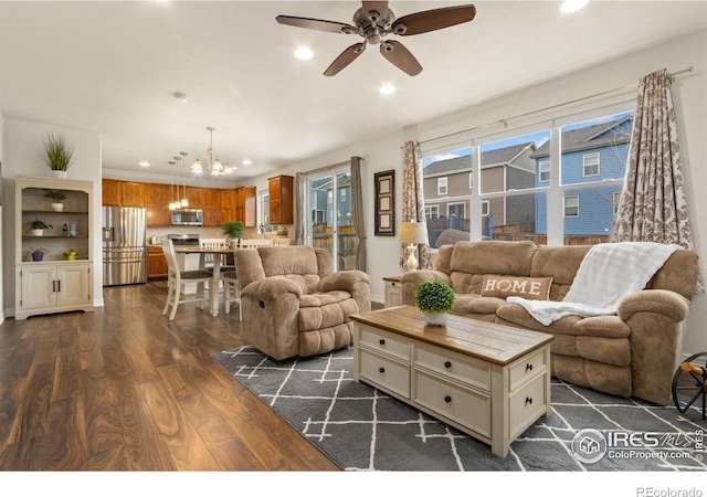 living room featuring recessed lighting, ceiling fan with notable chandelier, and dark wood finished floors