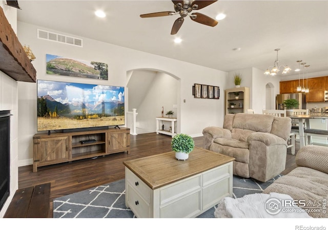 living room featuring visible vents, recessed lighting, arched walkways, dark wood-type flooring, and ceiling fan with notable chandelier