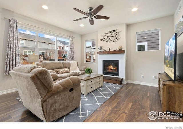 living area featuring dark wood-style flooring, baseboards, ceiling fan, recessed lighting, and a glass covered fireplace