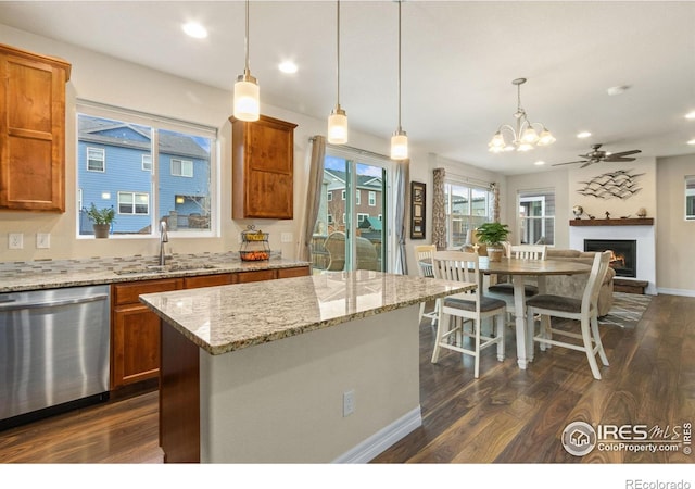 kitchen featuring dishwasher, dark wood finished floors, a sink, ceiling fan with notable chandelier, and brown cabinetry