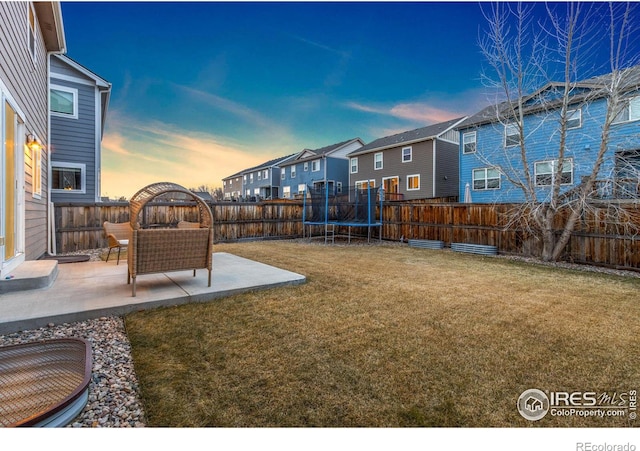 view of yard with a residential view, a trampoline, a fenced backyard, and a patio area